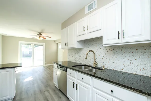 a kitchen with granite countertop white cabinets and a sink