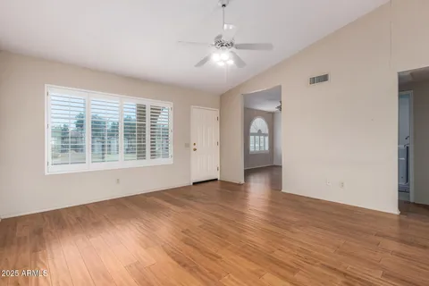 a view of an empty room with a window and wooden floor