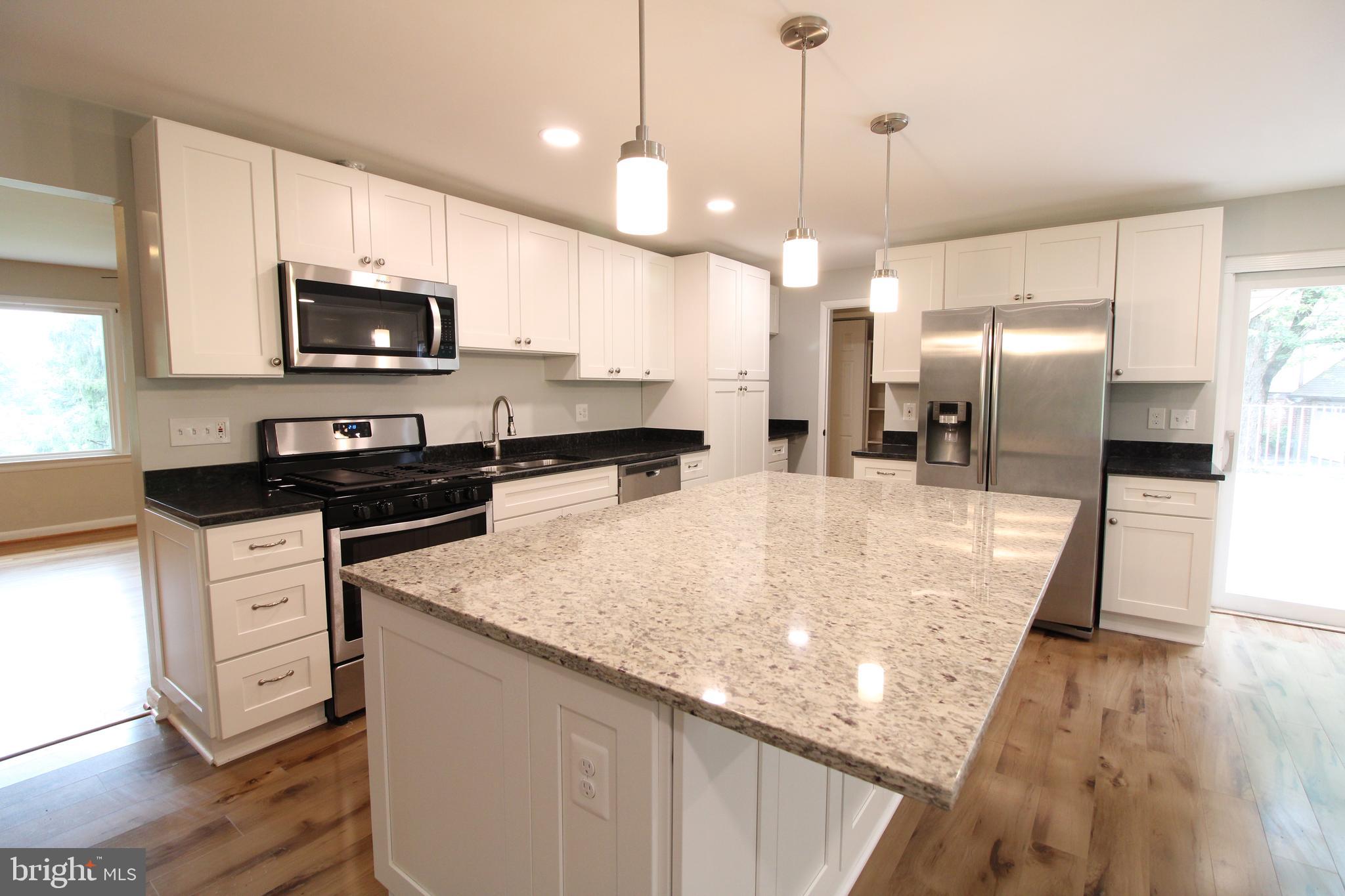 a kitchen with stainless steel appliances kitchen island granite countertop a sink a stove and a microwave