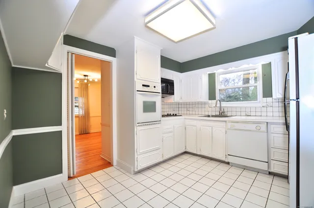 a view of a kitchen with refrigerator and white cabinets