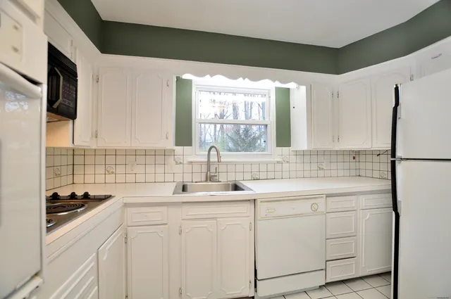a kitchen with white cabinets a sink a window and stainless steel appliances