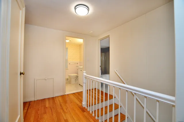 an empty room with wooden floor stairs and a way to other door