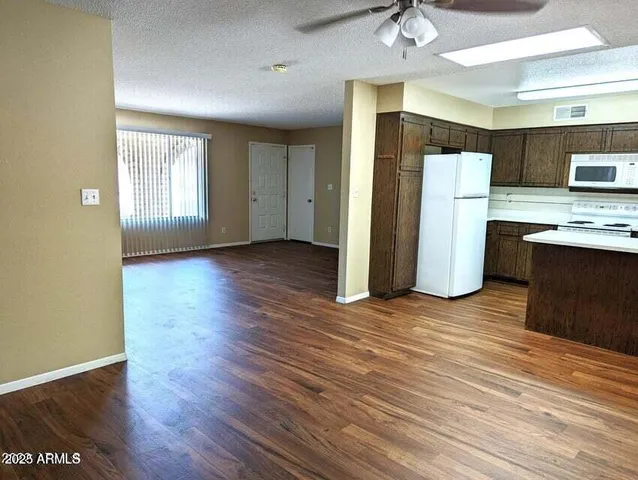 a view of a kitchen with a fridge and wooden floor