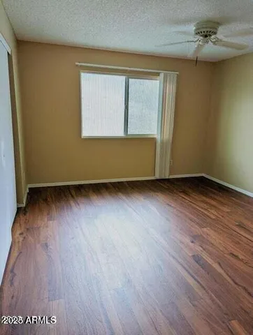 an empty room with wooden floor fan and windows