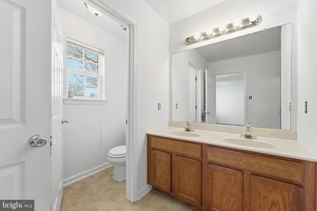 a spacious bathroom with a double vanity sink a mirror and a toilet
