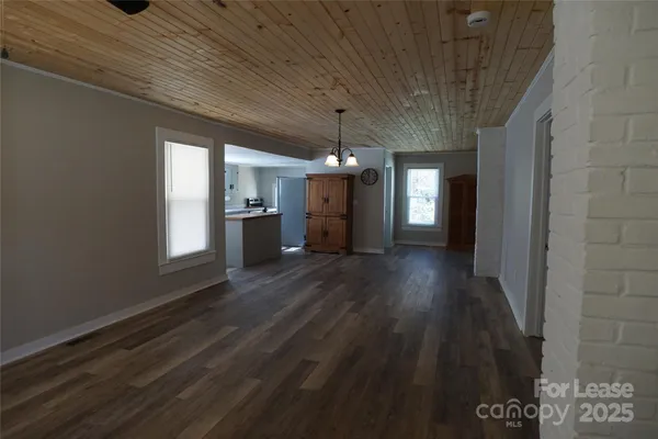 a view of a hallway with wooden floor and a kitchen space