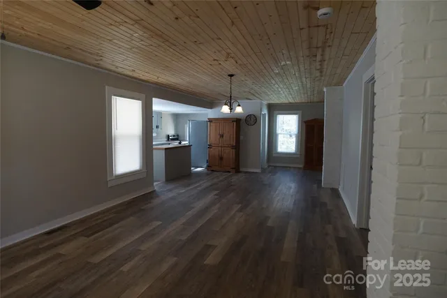 a view of a hallway with wooden floor and a kitchen space