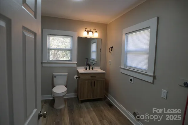 a bathroom with a sink toilet a mirror and window
