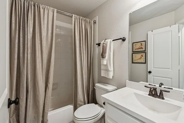 a bathroom with a sink a toilet a mirror and shower curtain