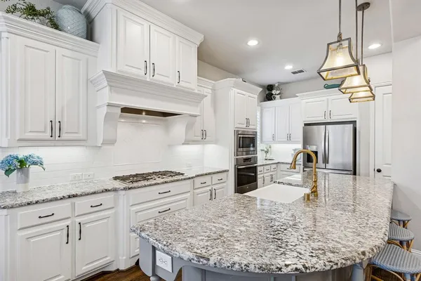 a kitchen with kitchen island granite countertop a sink a stove and cabinets