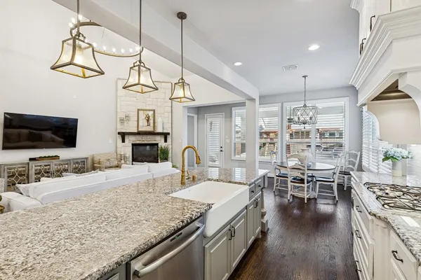 a kitchen with stainless steel appliances granite countertop a stove top oven a sink a dining table and chairs with wooden floor