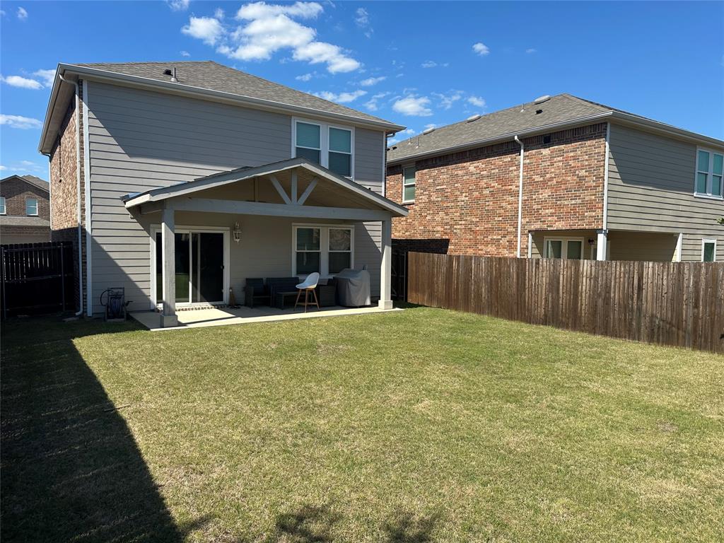 611 Colgate Circle Princeton, TX 75407 - Photo 2 of 9 Expansive lawn with a wooden privacy fence, a covered patio with a concrete slab, and sliding glass doors leading into the residence