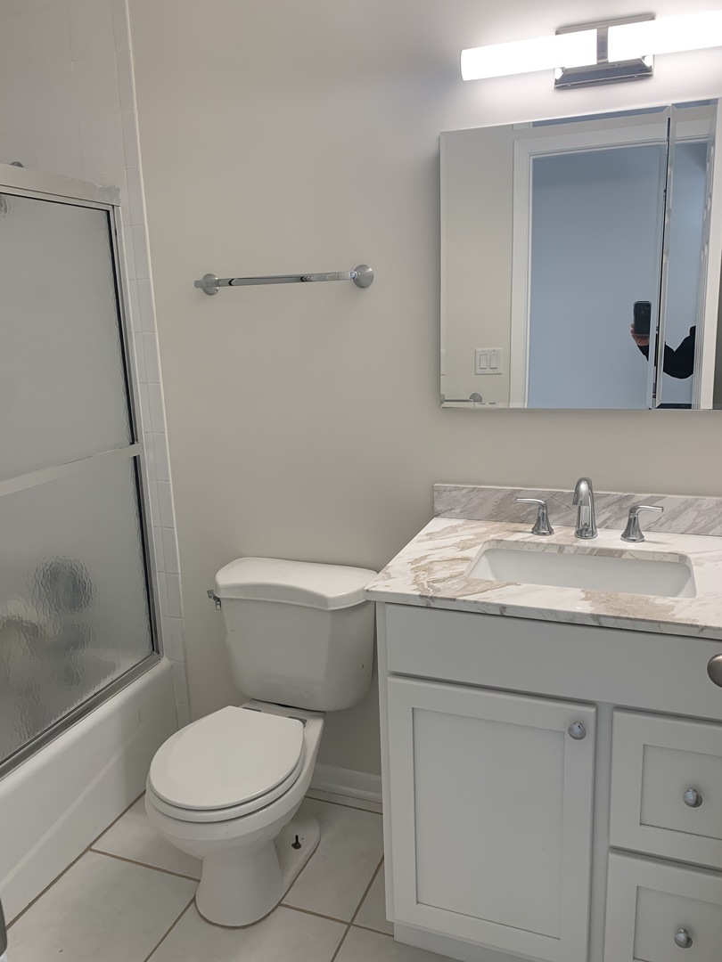 1149 Miller Lane, Unit 212 Buffalo Grove, IL 60089 - Photo 5 of 9 a bathroom with a granite countertop toilet sink and mirror