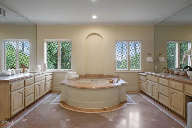 a spacious bathroom with a granite countertop sink a large mirror a bathtub and window