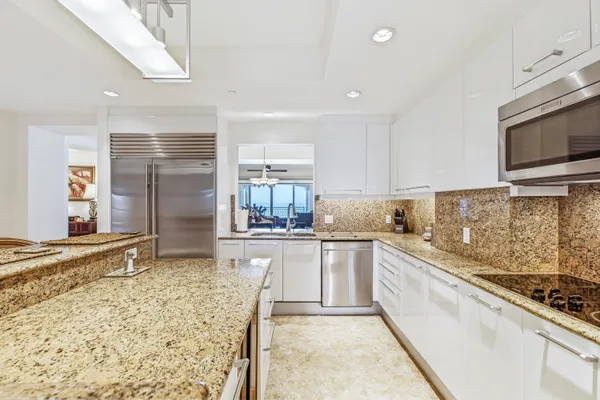 a kitchen with stainless steel appliances kitchen island granite countertop a sink stove and refrigerator