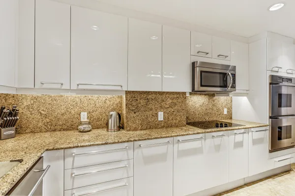 a kitchen with granite countertop white cabinets and stainless steel appliances