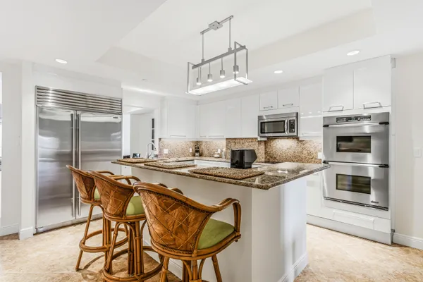 a kitchen with stainless steel appliances granite countertop a stove a sink a oven a dining table and chairs with wooden floor