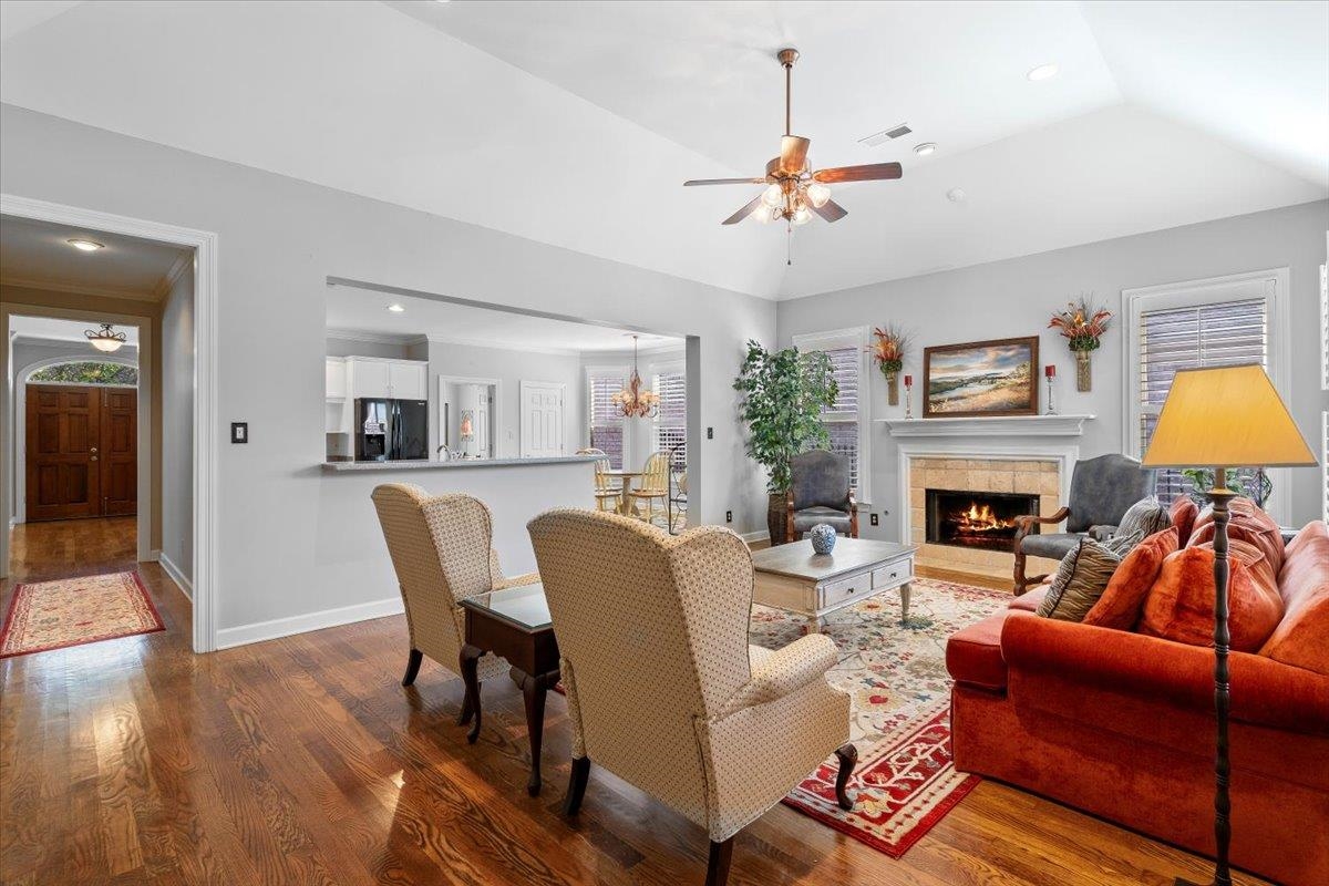 1495 Kimbrough Road Germantown, TN 38138 - Photo 15 of 31 Living room with visible vents, baseboards, wood finished floors, a tiled fireplace, and ceiling fan with notable chandelier