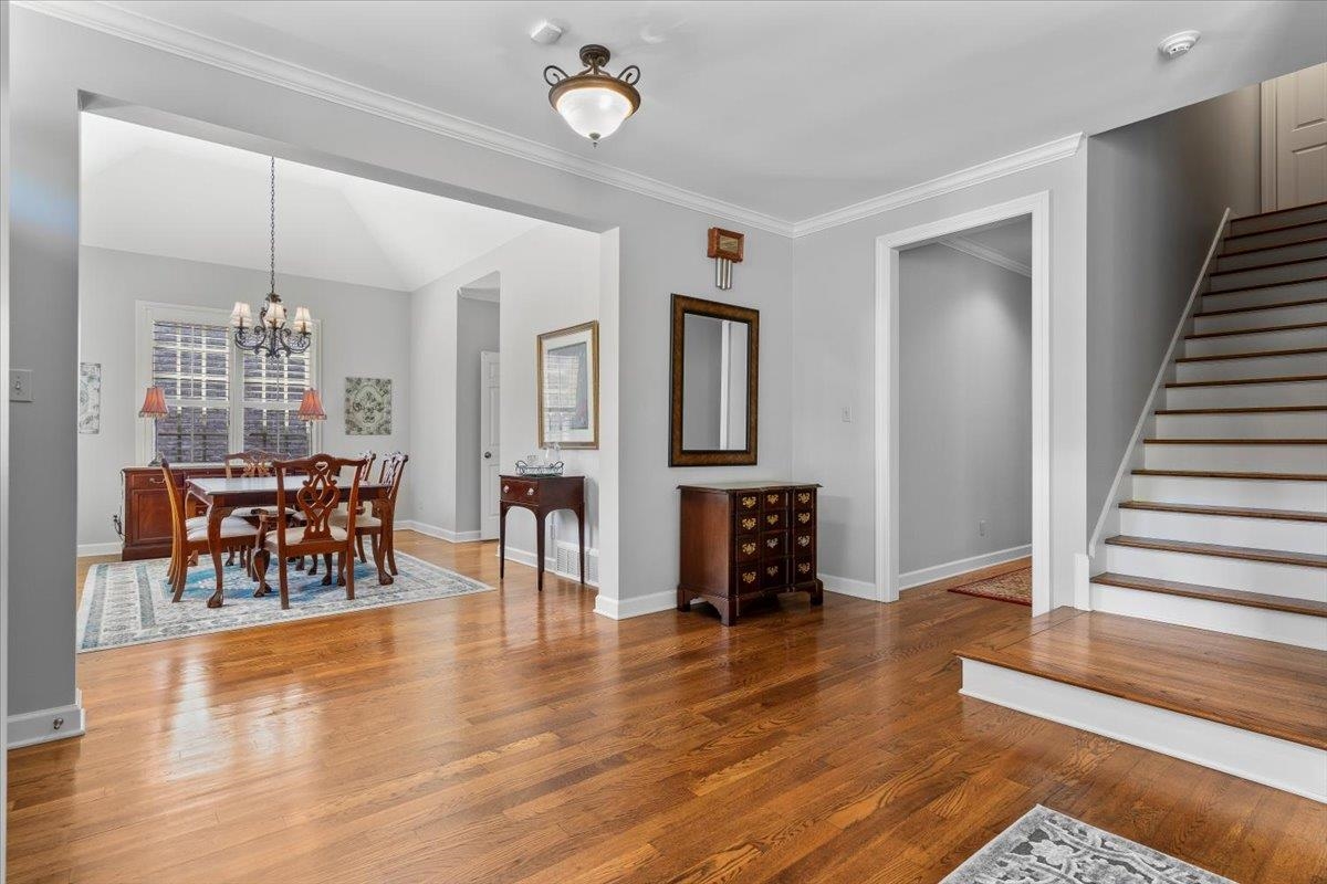 1495 Kimbrough Road Germantown, TN 38138 - Photo 3 of 31 Dining room with crown molding, stairway, wood finished floors, baseboards, and an inviting chandelier