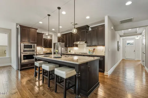 a kitchen with stainless steel appliances granite countertop a sink a stove and a wooden floors