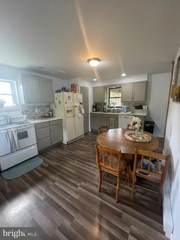 a kitchen with stainless steel appliances kitchen island granite countertop a table chairs and a refrigerator
