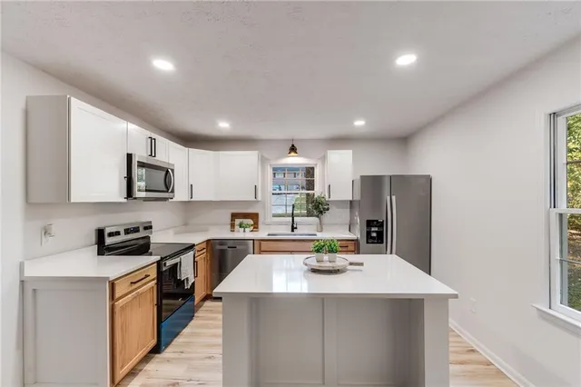 a kitchen with stainless steel appliances kitchen island granite countertop a sink dishwasher stove top oven and refrigerator with wooden floor