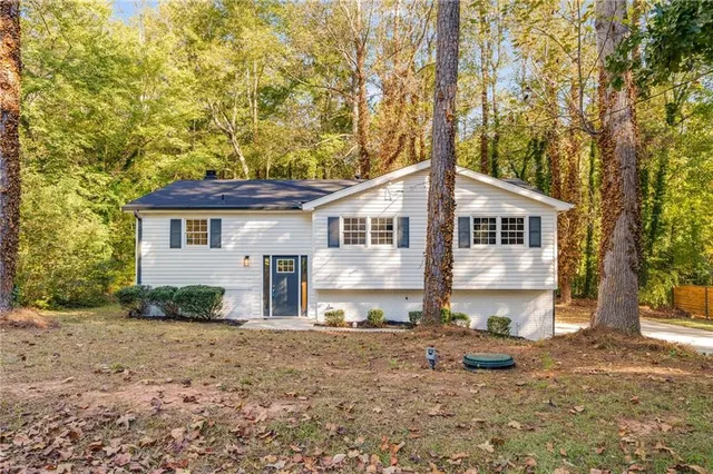 a front view of a house with a yard and a tree