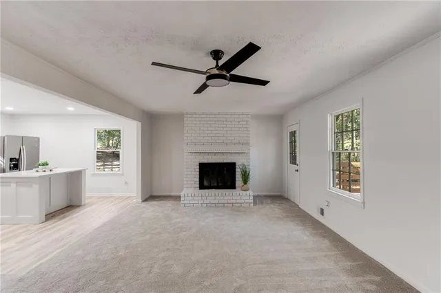 a view of a livingroom with a fireplace a ceiling fan and windows