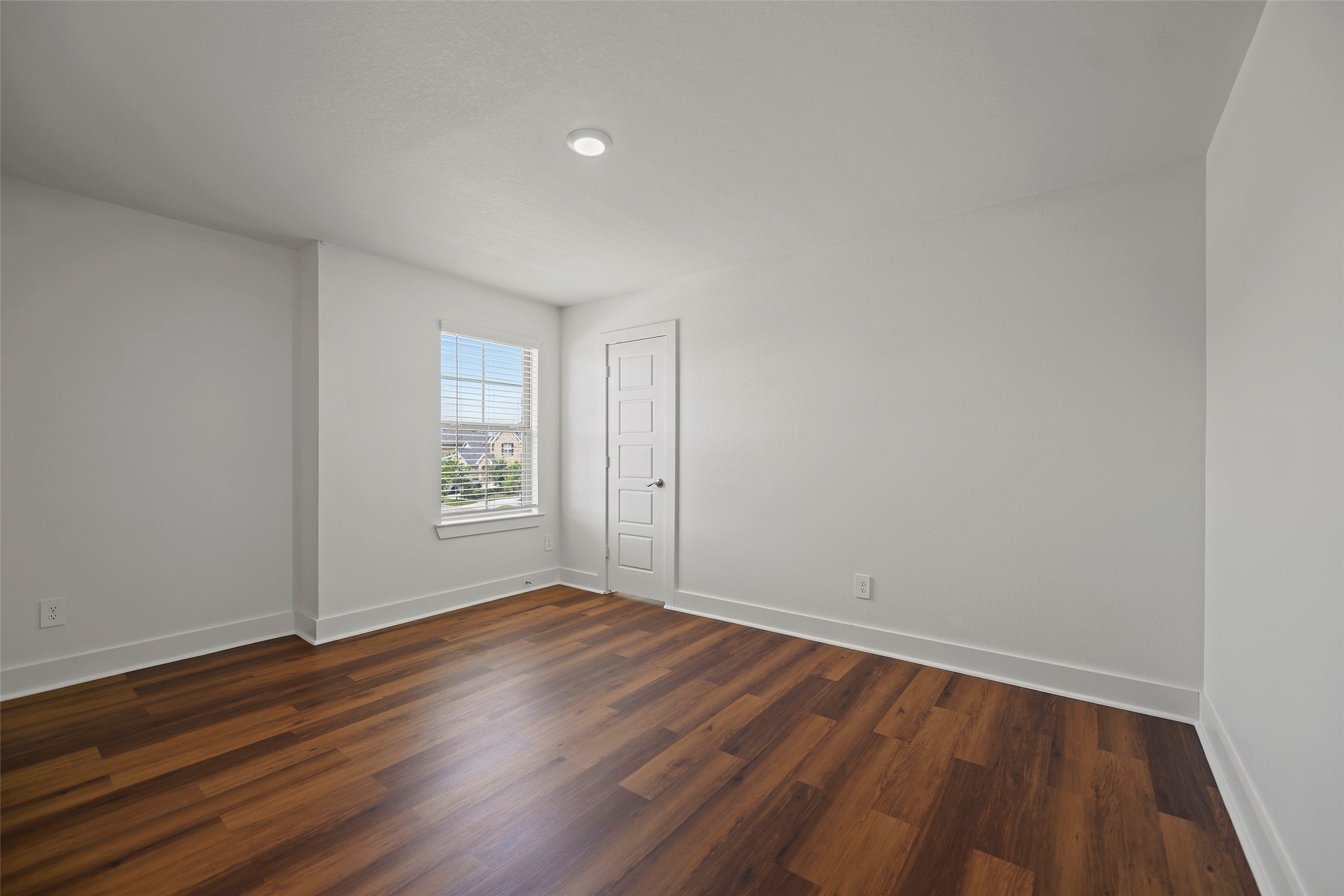 10603 Whitejacket Conroe, TX 77385 - Photo 9 of 42 This third bedroom features bright white walls, rich wood flooring, and a large window allowing ample natural light. A modern white door adds a sleek touch, creating a clean and inviting space.
