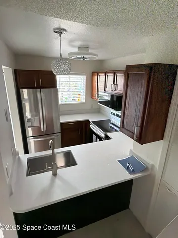 a kitchen with stainless steel appliances a refrigerator a sink a stove and white cabinets