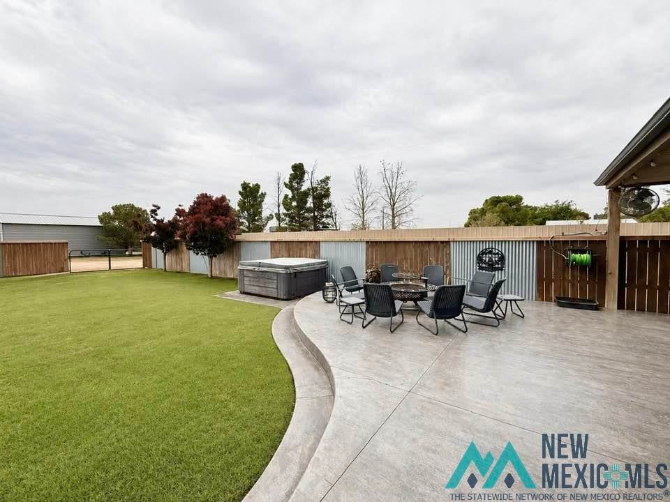 5404 Sioux Road Carlsbad, NM 88220 - Photo 73 of 100 Spacious backyard featuring a large concrete patio with a curved border, extensive lawn, and a wood-paneled spa