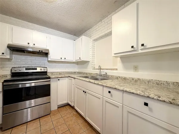 a kitchen with granite countertop white cabinets and a stove