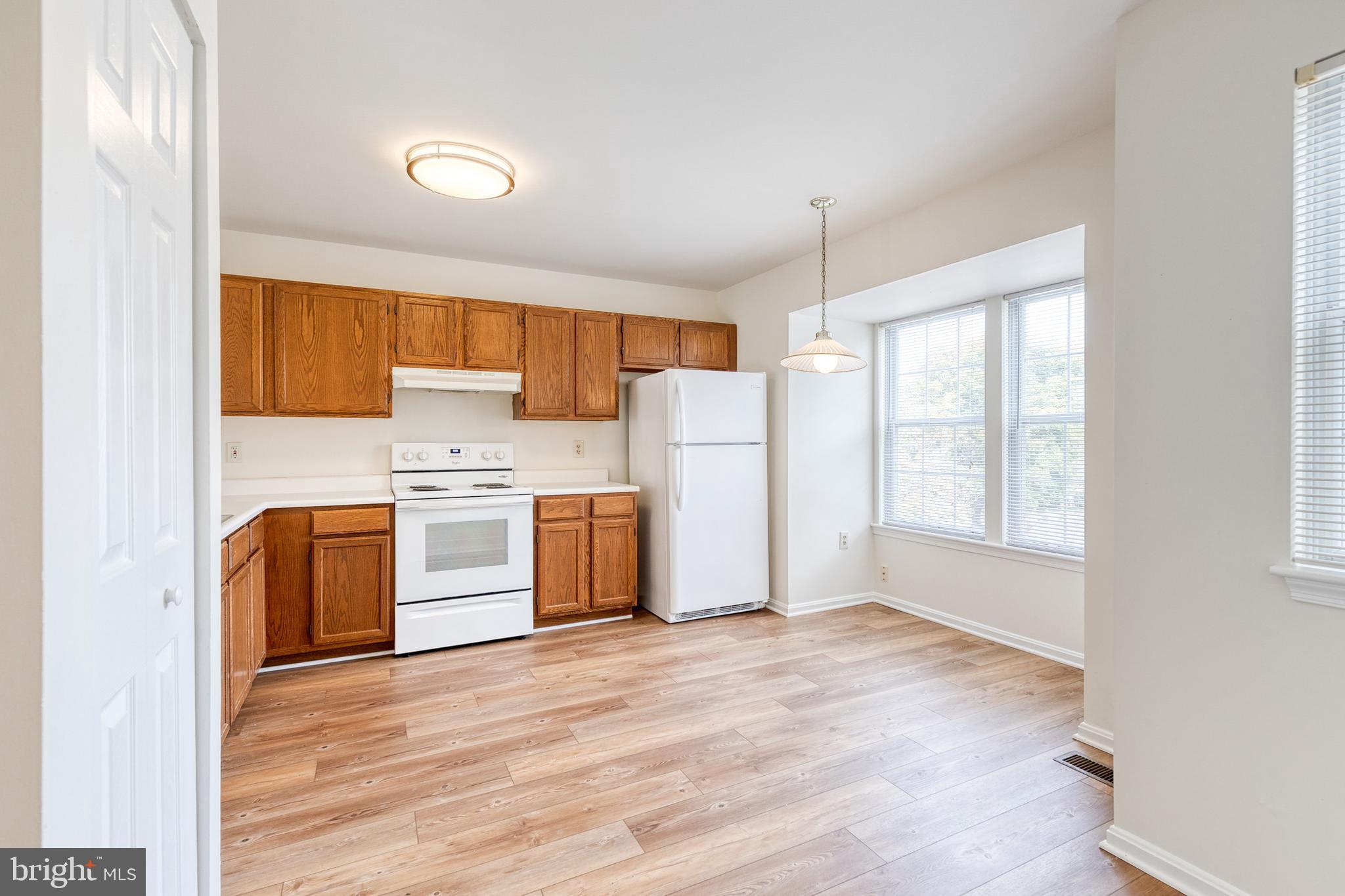 611 Brickston Road Reisterstown, MD 21136 - Photo 6 of 16 a kitchen with a refrigerator a stove top oven a sink and dishwasher with wooden floor