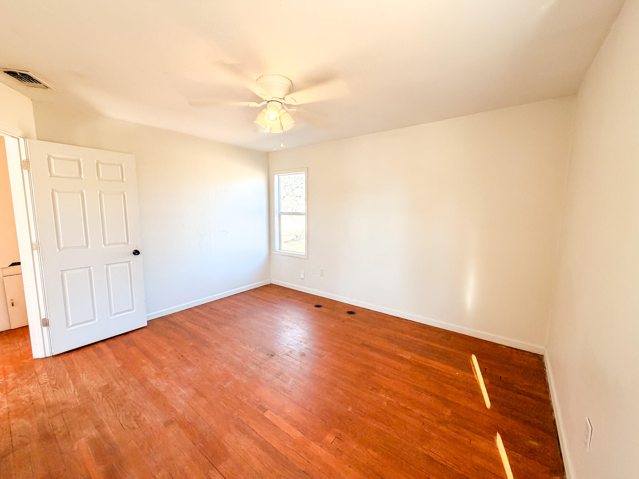 2616 38th Street Lubbock, TX 79413 - Photo 7 of 12 an empty room with wooden floor and fan