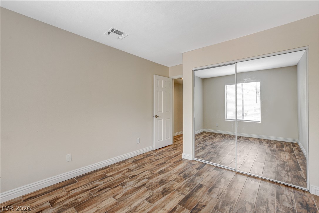 7200 West Pirates Cove Road, Unit 1026 Las Vegas, NV 89145 - Photo 20 of 35 This spacious bedroom features stylish wood-look tile flooring and a mirrored closet for added depth.