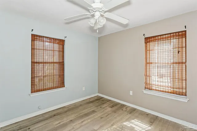 a view of an empty room with window and wooden floor