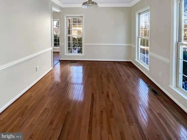 an empty room with wooden floor fireplace and windows