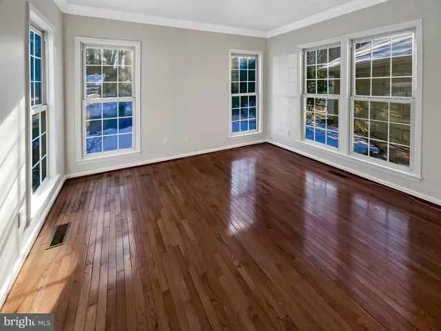 a view of an empty room with wooden floor and windows