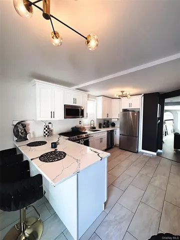 a kitchen with stainless steel appliances kitchen island granite countertop a stove a sink dishwasher and a refrigerator with wooden floor