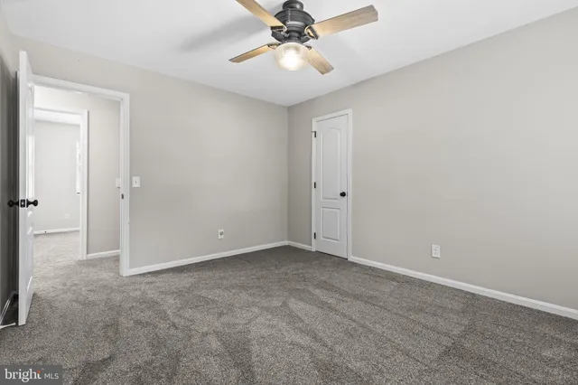 a view of an empty room and chandelier fan