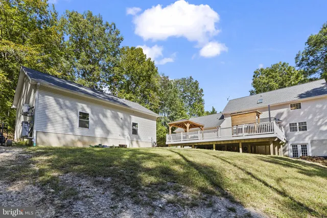 a view of a white house next to a yard with big trees