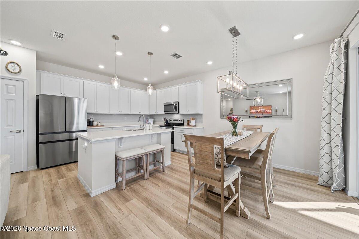 881 Covington Court Rockledge, FL 32955 - Photo 9 of 30 a kitchen with a dining table chairs wooden floor cabinets appliances and a window