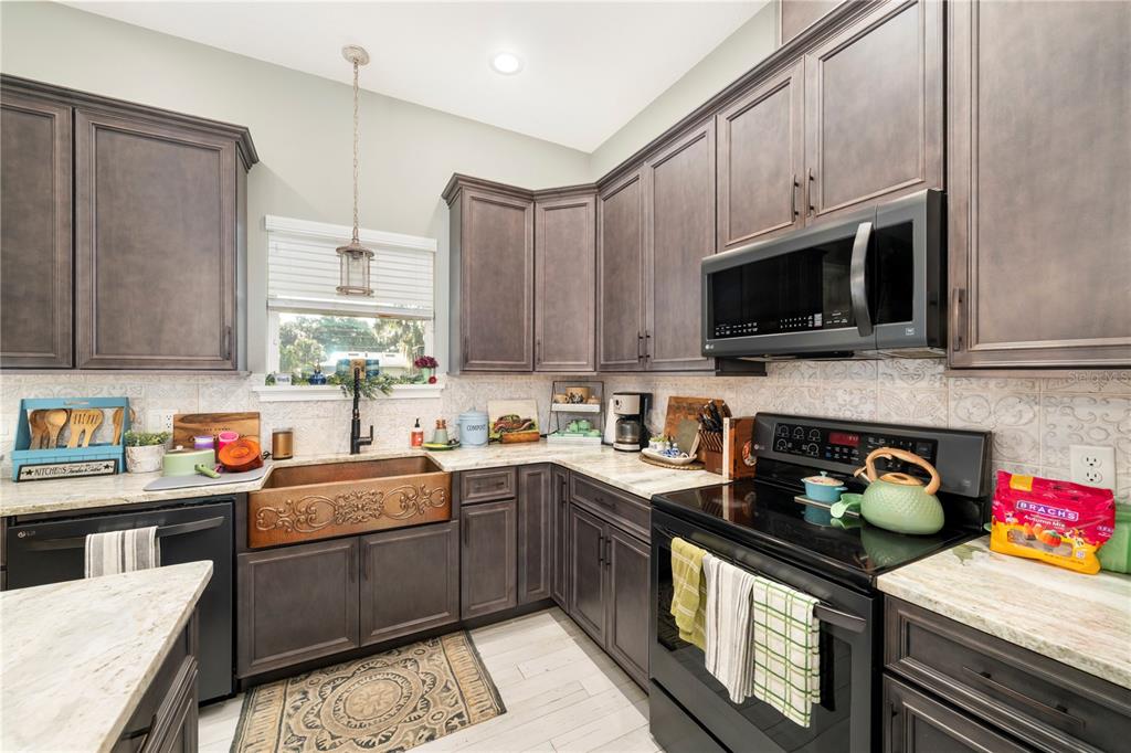 35638 Calla Court Leesburg, FL 34788 - Photo 13 of 44 a kitchen with stainless steel appliances a sink a stove a microwave a refrigerator and cabinets