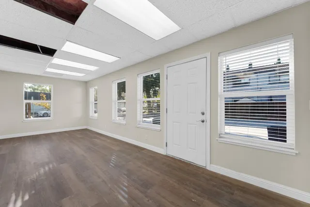 a view of an empty room with wooden floor and a window