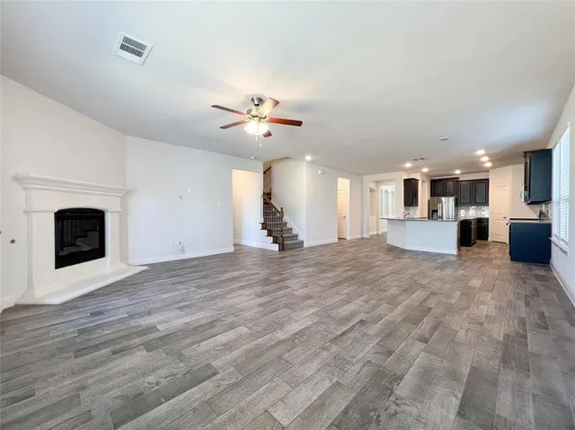 a view of a livingroom with a fireplace a chandelier fan and wooden floor