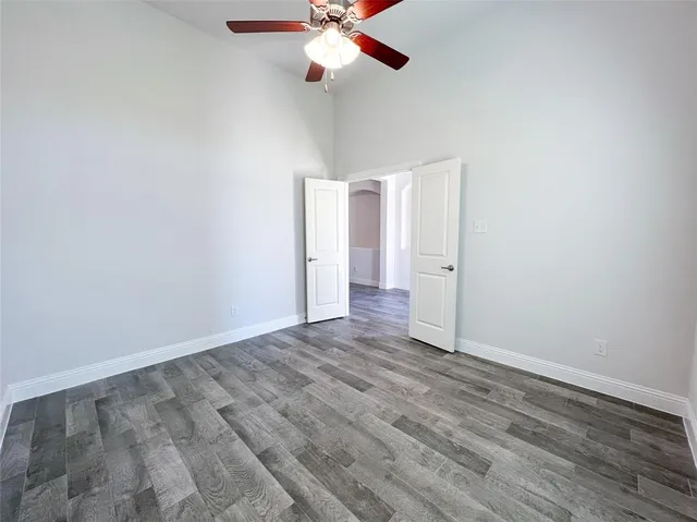 an empty room with wooden floor ceiling fan and window