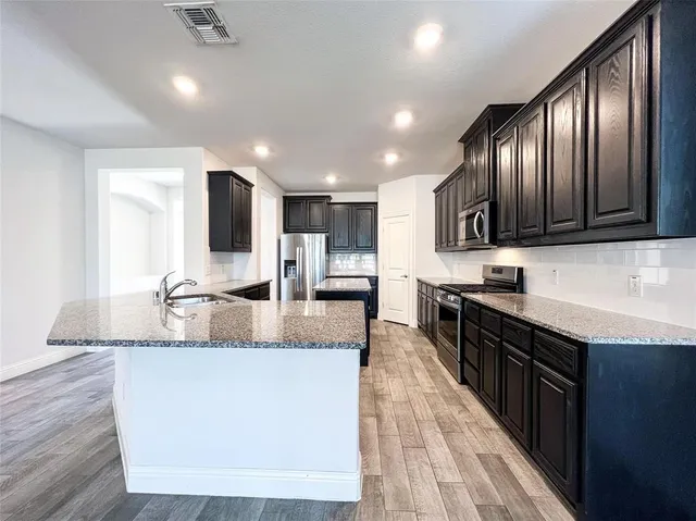 a large kitchen with granite countertop lots of counter space and stainless steel appliances