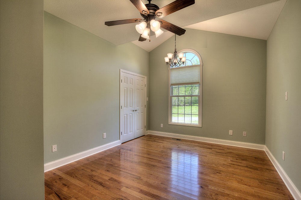 1400 Grimes Road Loudon, TN 37774 - Photo 25 of 32 an empty room with wooden floor chandelier fan and windows