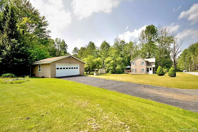 a view of a house with a yard and a large tree