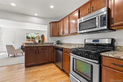a kitchen with stainless steel appliances granite countertop a stove top oven a sink dishwasher and cabinets with wooden floor